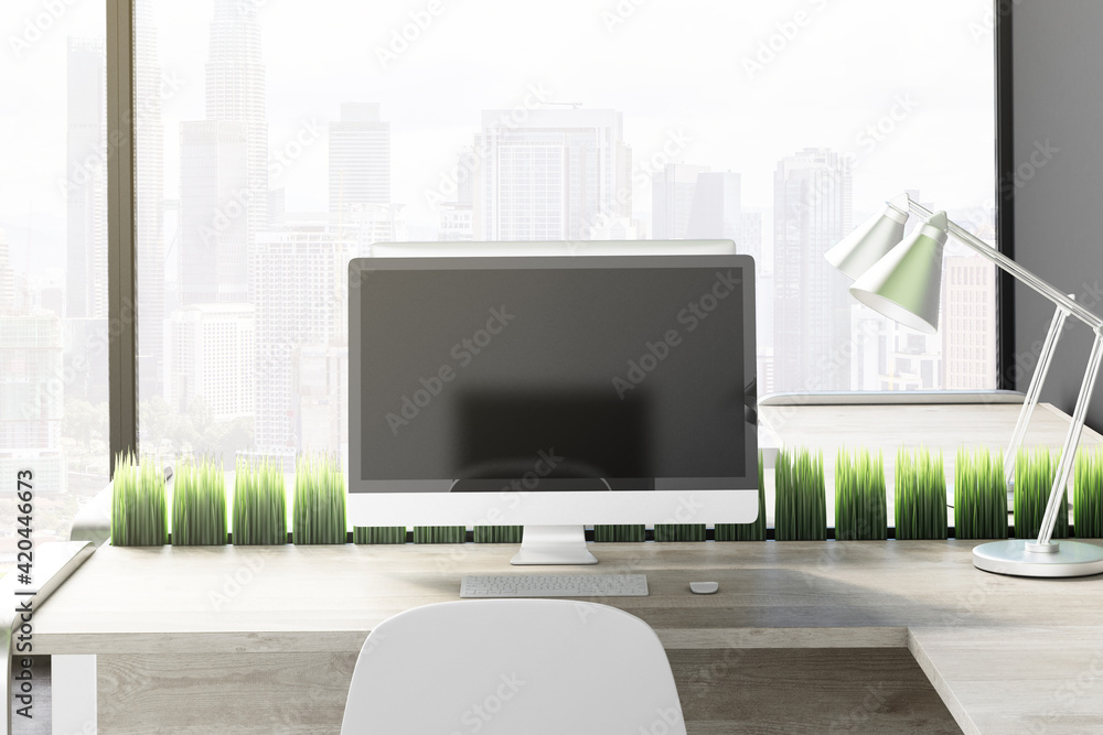 Poster blank black monitor screen with modern steel lamp and plants on office table in front of big window 
