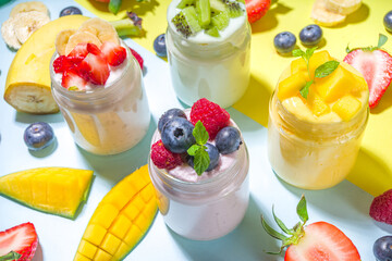 Set of various fruit and berry sweet yogurts in glass jars. Variety healthy Breakfast yoghurts with blueberry, strawberry, mango, kiwi, raspberry, with fresh fruits and berries