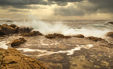 Beautiful seascape, ocean views, rocky coast, sunlight on the horizon. Composition of nature. Sunset scenery background. Cloudy sky. Water Reflection. California Seashore.