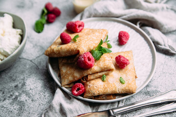 Crepes with homemade cottage cheese, raspberries a gray plate