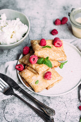 Crepes with homemade cottage cheese, raspberries a gray plate