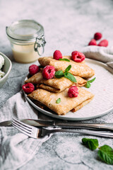Crepes with homemade cottage cheese, raspberries a gray plate