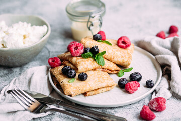 Crepes with homemade cottage cheese, raspberries a gray plate