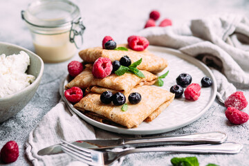Crepes with homemade cottage cheese, raspberries a gray plate
