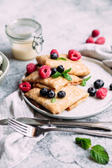 Crepes with homemade cottage cheese, raspberries a gray plate