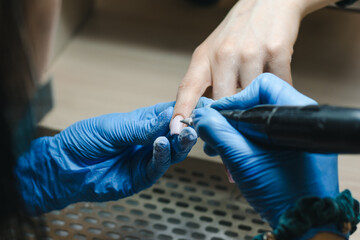 The manicurist removes the old gel from the nails using the hardware method closeup