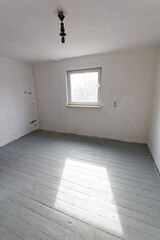 Puste pomieszczenie w trakcie remontu, z pojedynczym oknem.