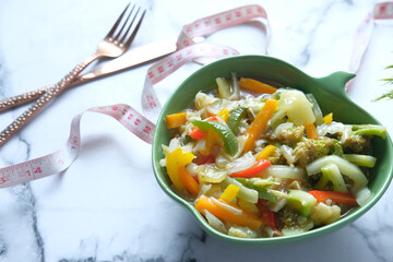 Fitness concept with mixed fresh vegetable and measurement tape on white 