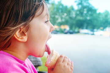 Little girl licks ice cream in waffle cone