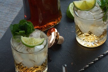 Alcoholic cocktail with rum and ice and mint on a dark background in a bar