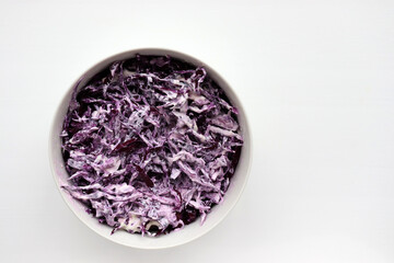 Easy homecooked creamy coleslaw from red cabbage in a bowl on white table background. Top view, copy space. Fresh vegetable salad with mayonnaise dressing. Flat lay food. Healthy eating concept
