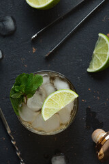 Alcoholic cocktail with rum and ice and mint on a dark background in a bar