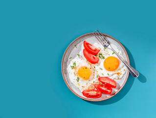 Two fried eggs with toast and vegetables on colorful background. Breakfast concept. Healthy vegetarian food.