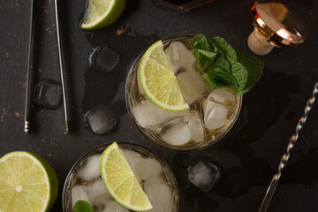 Alcoholic cocktail with rum and ice and mint on a dark background in a bar