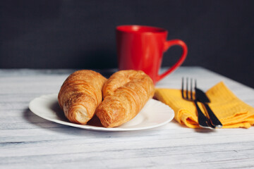 fresh croissant on a plate kitchen utensils coffee cup breakfast