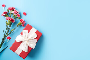 Concept of Mother's day holiday greeting gift with carnation bouquet on bright blue table background