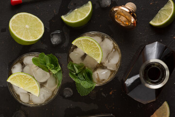 Alcoholic cocktail with rum and ice and mint on a dark background in a bar
