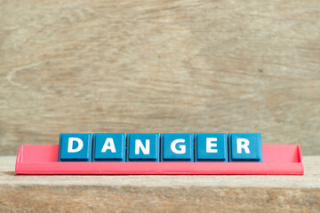 Obraz premium Tile alphabet letter with word danger in red color rack on wood background