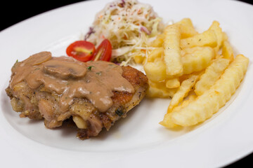Steak with mushroom sauce, french fries and salad on plate.