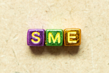 Metallic color alphabet letter block in word SME (abbreviation of Small and medium sized enterprises) on wood background