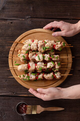 Woman serving delicious kebab on wooden skewers