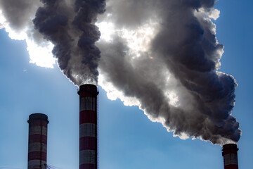 A close-up of the smoking chimneys of a coal-fired power plant. Made in a sunny day, deep blue skies