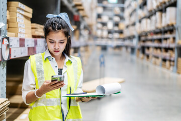 Young asian woman worker uses the phone for business contacts and holding clipboard to checking...