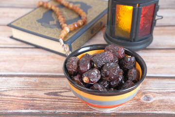 close up of fresh date fruit in a bowl and quran on background 