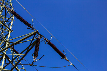 Close-up of insulators on high voltage pylons against the background of blue sky. Made in a sunny day, deep blue skies