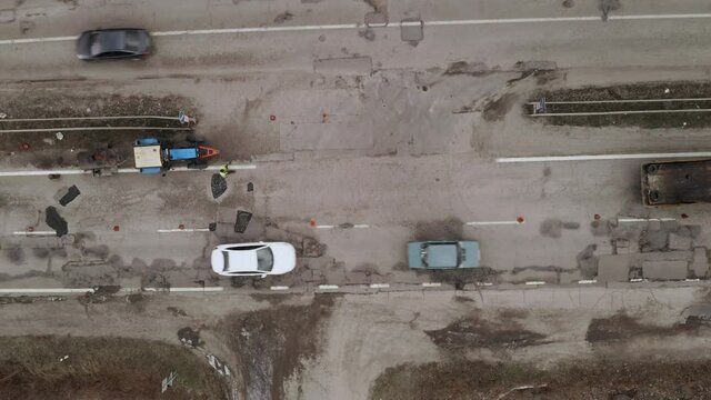 Pit repair of the broken section of the track - Road workers manually fill the pits and potholes on the road surface. Workers repair highway surface - aerial drone Overhead Shot