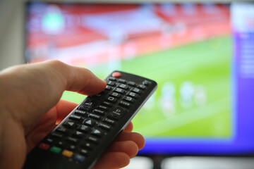 Fußball im TV schauen. Mann mit Fernbedienung im Vodergrund.