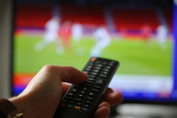 Fußball im TV schauen. Mann mit Fernbedienung im Vodergrund.