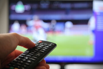 Fußball im TV schauen. Mann mit Fernbedienung im Vodergrund.