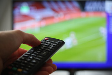 Fußball im TV schauen. Mann mit Fernbedienung im Vodergrund.