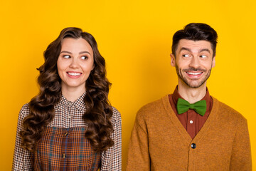Portrait of two positive persons toothy smile look interested each other isolated on yellow color...