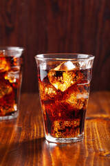 glass of cold cola soft drink with ice on wooden background