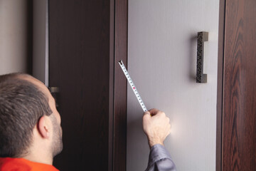 Man using tape measure while installing new furniture in home.