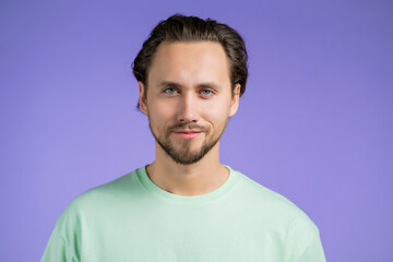 Fototapeta premium Portrait of cheerful european man looking to camera.Young handsome kind guy smiling in studio on violet background.