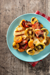 GRILLED FRUIT on a blue plate on wooden table. Top view