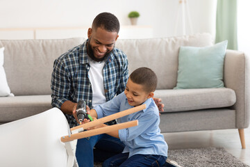 African American Father And Son Fixing Table Together At Home