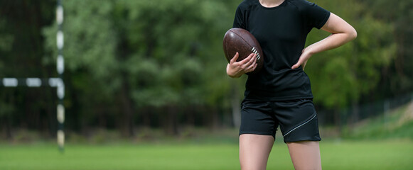 Girl holds a rugby ball, isolated on a green background. Woman sport concept