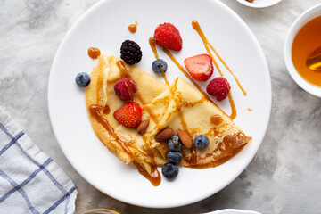 Overhead view of  plate with breakfast crepe and berries, blini