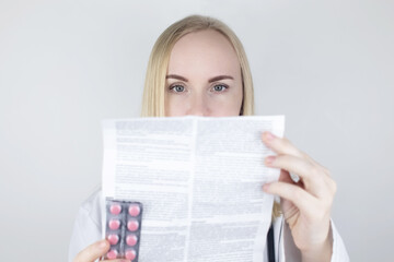 The doctor on a white background reads the instructions for medicines. The specialist looks at the...