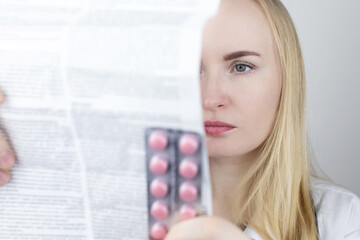 The doctor on a white background reads the instructions for medicines. The specialist looks at the...