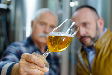 brewer tilting glass to inspect beer