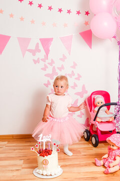 photo shoot of little girl in a pink curvy skirt for her birthday in one year. baby and cream cake