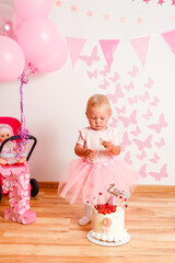 celebrating a birthday in one year to little girl. white cake with strawberries and pink decoration butterflies and balls