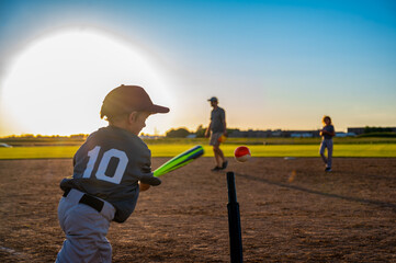 Youth batter hitting a tee ball into an open field at practice
