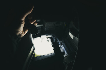 checking a battery under a vehicle hood with a flashlight at night