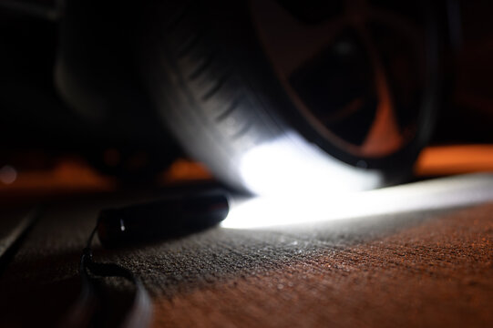 Flashlight pointing towards a vehicle flat tire at night